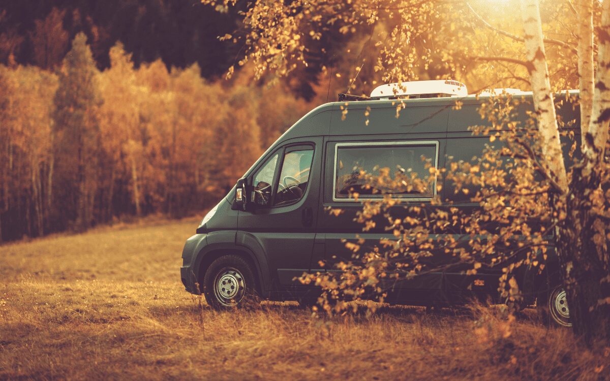 Camper aparcada en un camino con arboles y toque otoñal